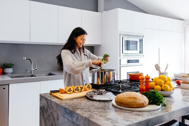 Femme avec sourire dans la cuisine qui découpe et cuisine avec amour