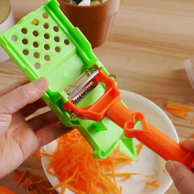 Éplucheur à légumes ergonomique utilisé pour trancher une carotte, outil pratique pour une découpe rapide et précise