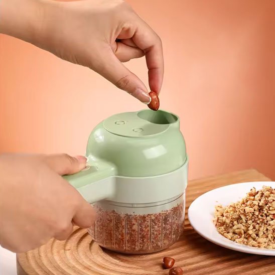 Coupe légumes électrique utilisée pour broyer des noix ou des noix dans un récipient transparent.