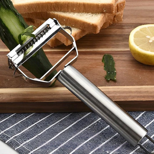 Eplucheur multifonction ultra‑tranchant en acier inoxydable posé sur une planche de cuisine avec légumes.
