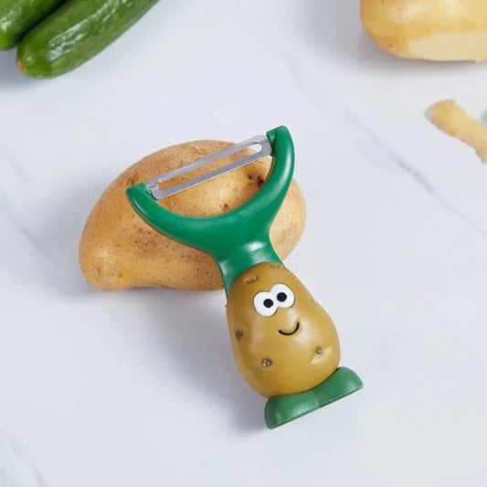 Eplucheur en forme de patate souriante posé sur une table à côté d’une pomme de terre.