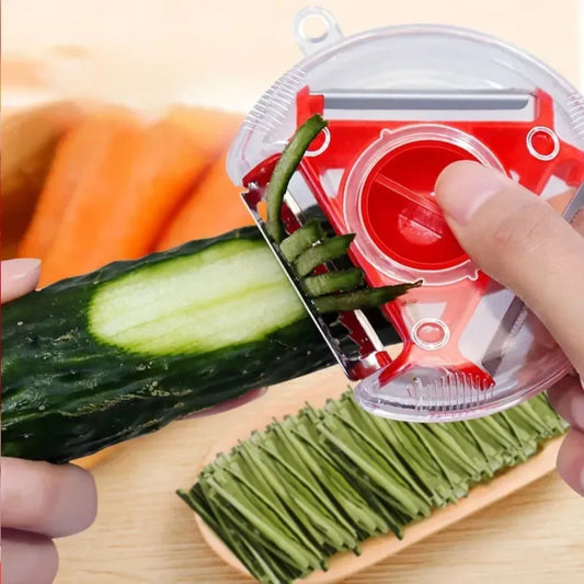 Éplucheur triangulaire rouge 3‑en‑1 pour légumes, utilisé sur un concombre dans une cuisine moderne.