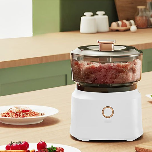 Hachoir à viande électrique sur un plan de travail moderne avec viande hachée, spaghetti et légumes.