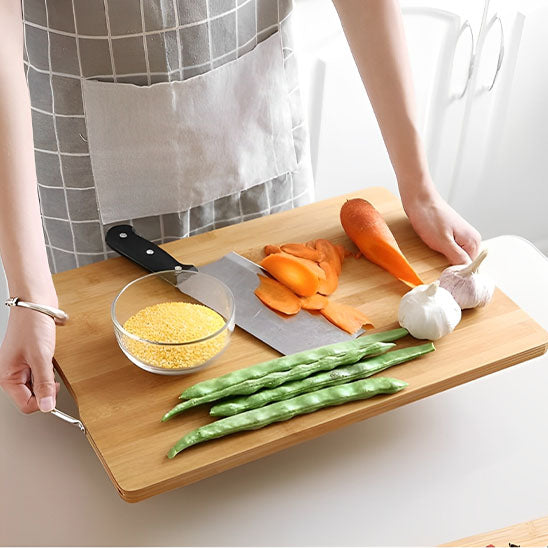 Planche à découper en bois avec carottes et asperges prêtes à être coupées pour la préparation des repas.