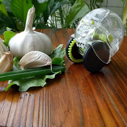Presse-ail transparent posé sur des légumes frais avec ail  – gadget de cuisine idéal pour préparer l’ail avec des produits naturels.


