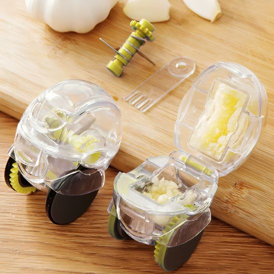 Deux presse-ails roulants transparents avec composants verts, l’un ouvert avec ail écrasé, l’autre fermé – outil de cuisine ergonomique avec brosse de nettoyage.