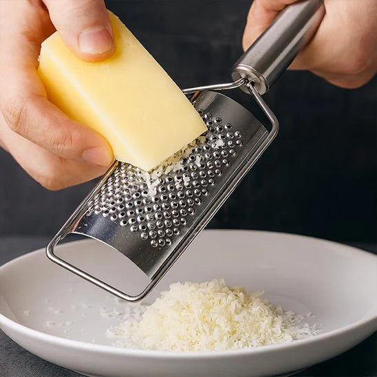 Gros plan sur une râpe à fromage inox produisant des filaments fins – accessoire cuisine pour parmesan et gruyère