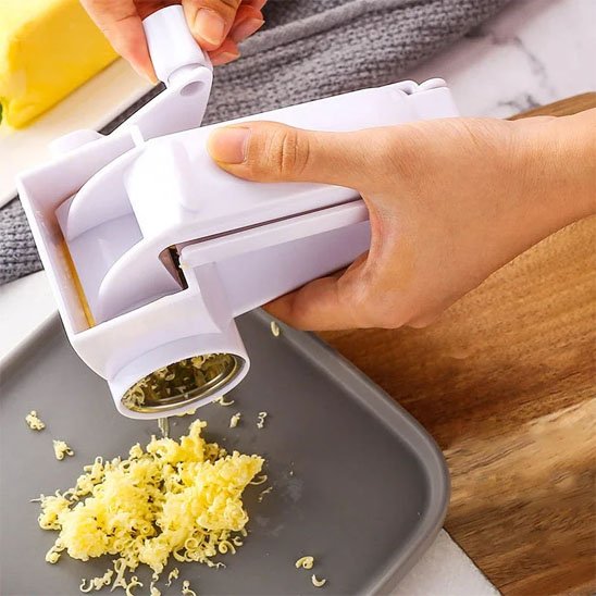 Râpe à fromage en inox utilisée pour obtenir des grains fins de fromage sur une assiette grise