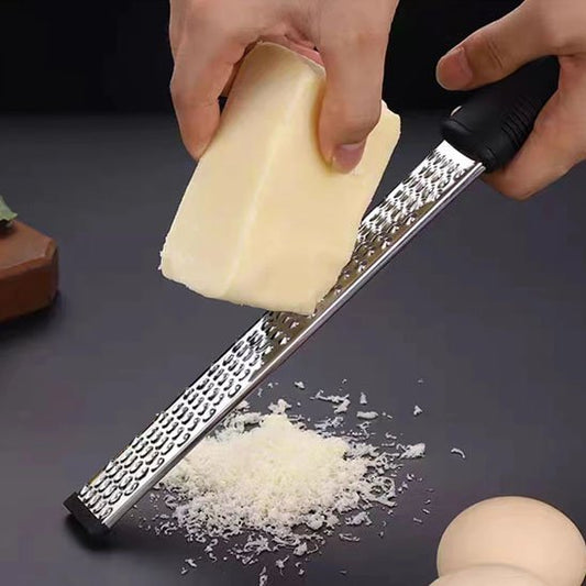 Râpe à fromage premium en inox utilisée pour râper du parmesan en copeaux fins.