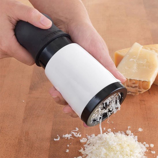 Râpe à fromage rotative blanche et noire utilisée pour râper du parmesan sur surface en bois