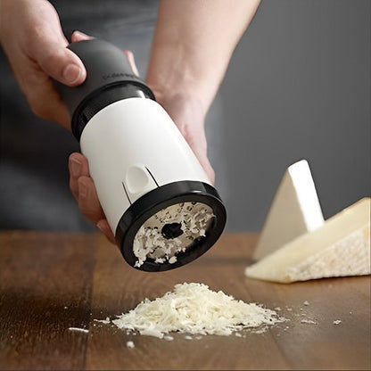 Râpe à fromage rotative noire et blanche utilisée pour râper du parmesan sur planche en bois