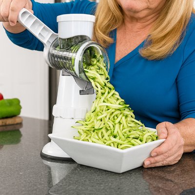 Préparation de nouilles de courgette avec une râpe à légumes manuelle à manivelle, tombe directement dans un bol blanc, parfaits pour vos préparations. 
